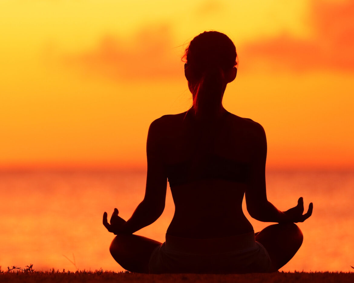 Wellness woman doing zen yoga meditation on beach